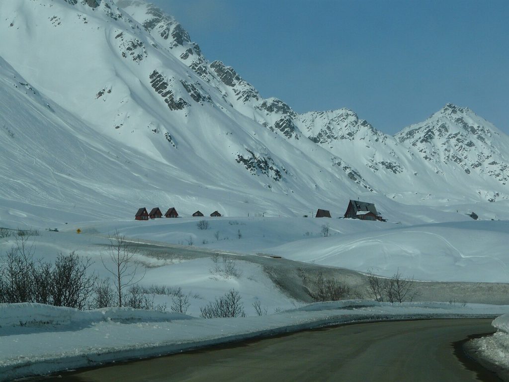 A winter scene at Hatcher Pass, Alaska provides weather-planning context. The historical image is not a current forecast, closure report, or approval to drive this road.