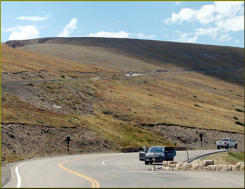 An archived mountain-road scene at Medicine Bow Curve, Colorado. The photographed vehicles do not establish payload, current road conditions, or route suitability.