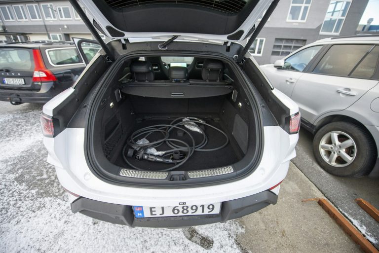 Open hatchback cargo area with charging cables on the floor in a snowy parking lot