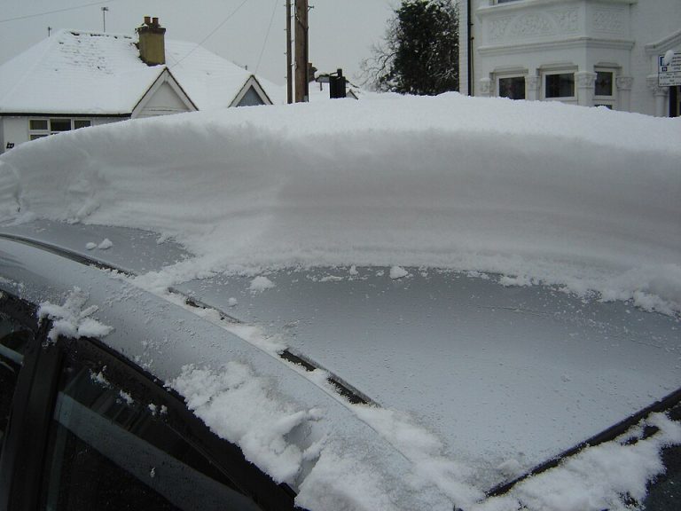 A parked car buried under a thick layer of snow